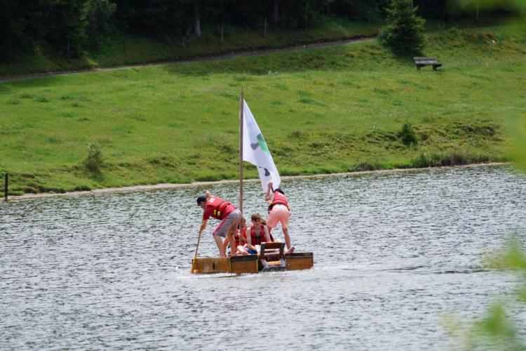 Jungschärler*innen mit fertig gebautem Boot oder Floss auf dem Fluss