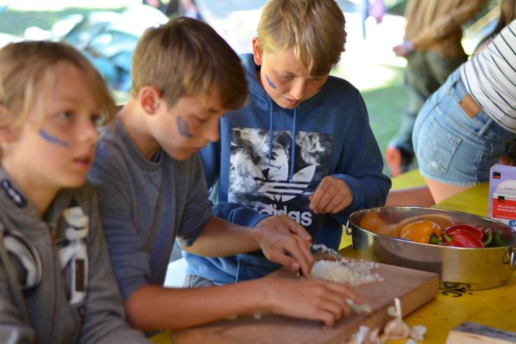 Teilnehmer*innen schneiden Zwiebeln und Gemüse